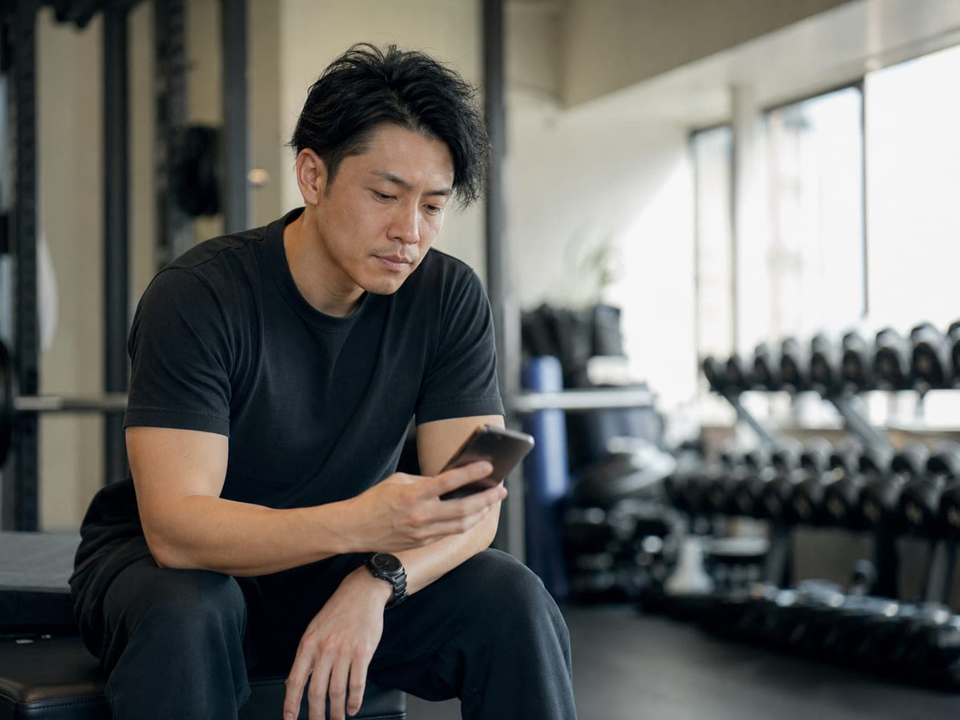 セッションの合間にスマートフォンを見て考えるトレーナー